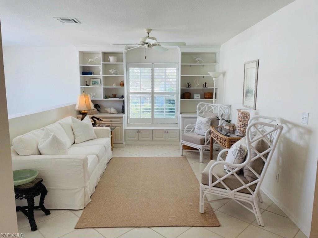 Living area featuring light tile patterned floors, ceiling fan, and built in features