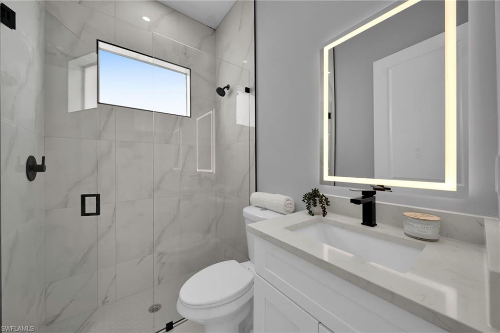 Bathroom featuring a marble finish shower and vanity