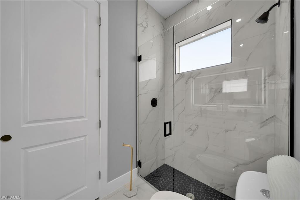 Full bathroom with toilet and a marble finish shower