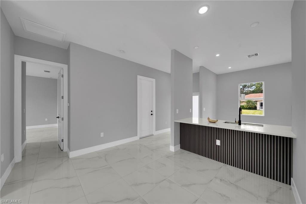 Kitchen featuring light marble finish flooring, light stone countertops, and recessed lighting