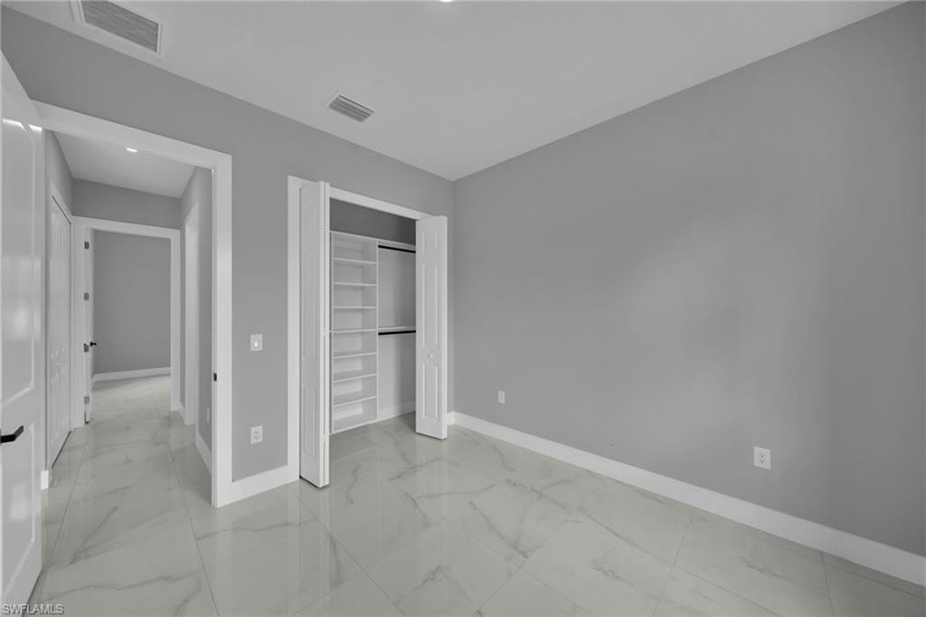 Unfurnished bedroom with light marble finish floors and a closet