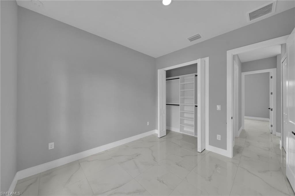 Unfurnished bedroom with light marble finish flooring and a closet