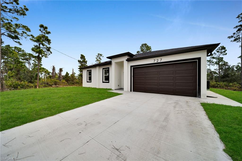 Prairie-style home featuring concrete driveway, a front lawn, stucco siding, and an attached garage