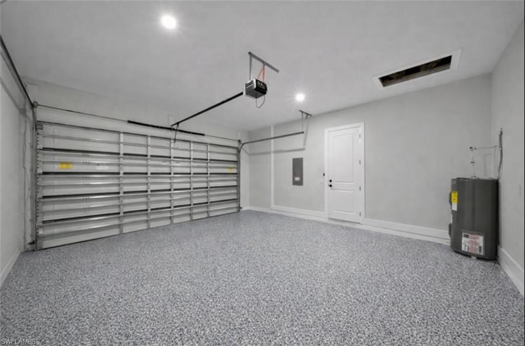 Garage with water heater, electric panel, and a garage door opener