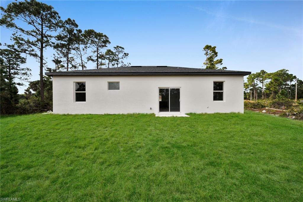 Back of house with a yard and stucco siding