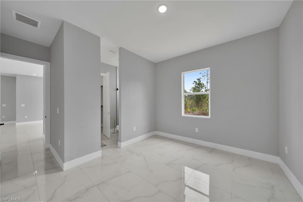 Empty room with light marble finish floors and recessed lighting