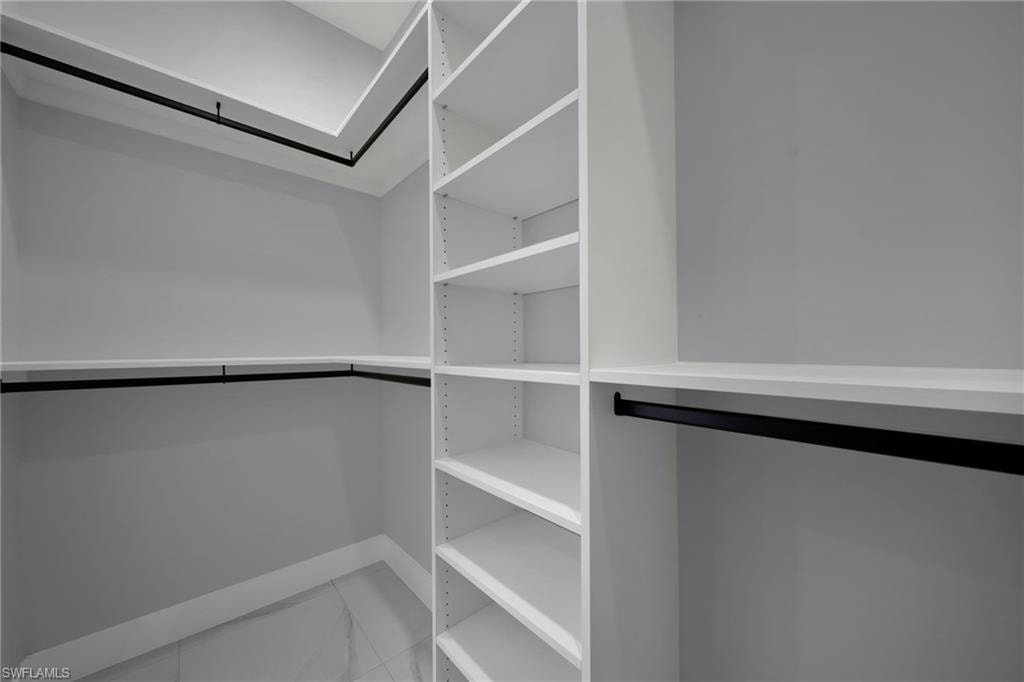 Spacious closet featuring marble finish floors