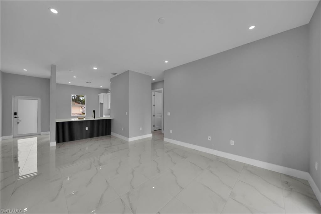 Unfurnished living room with recessed lighting and light marble finish flooring