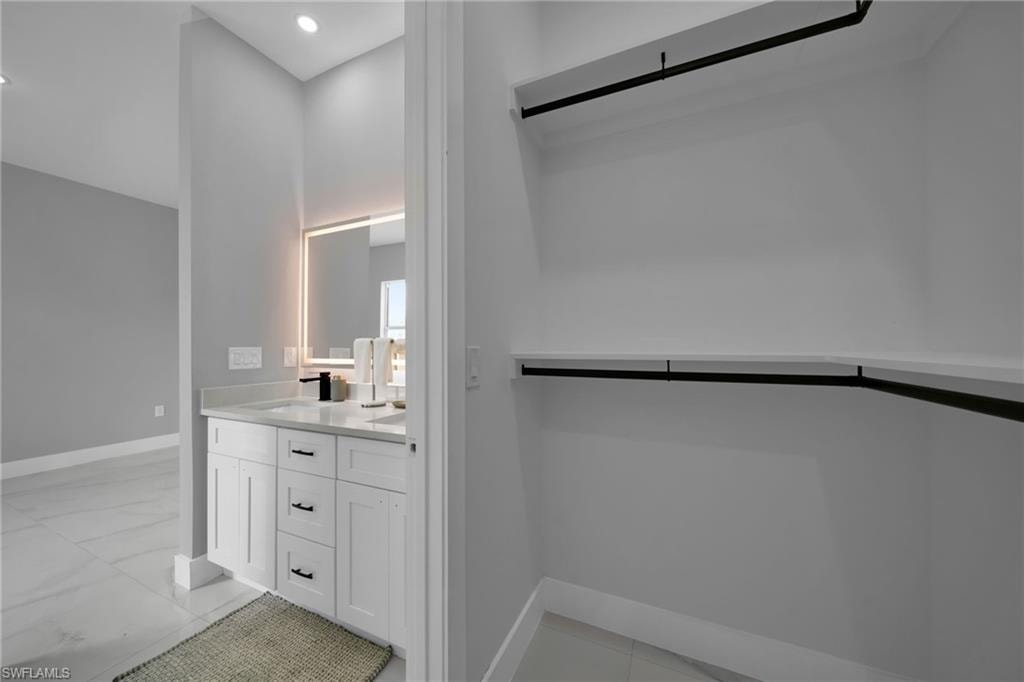 Full bathroom with double vanity and light marble finish flooring