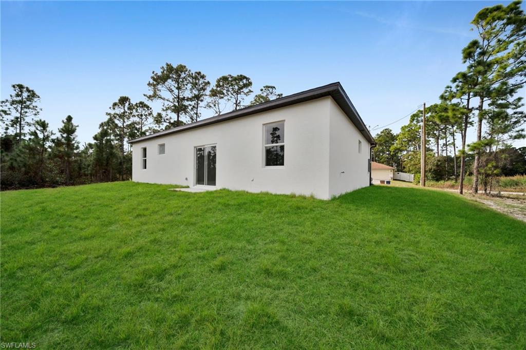 Rear view of house with a lawn and stucco siding