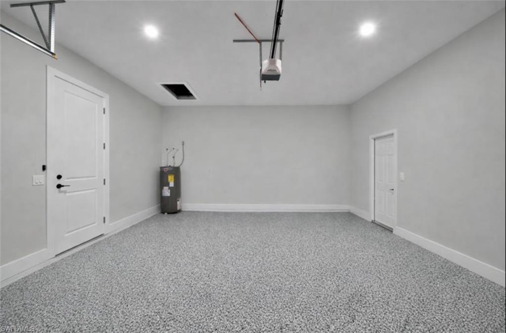 Garage featuring water heater, a garage door opener, and recessed lighting
