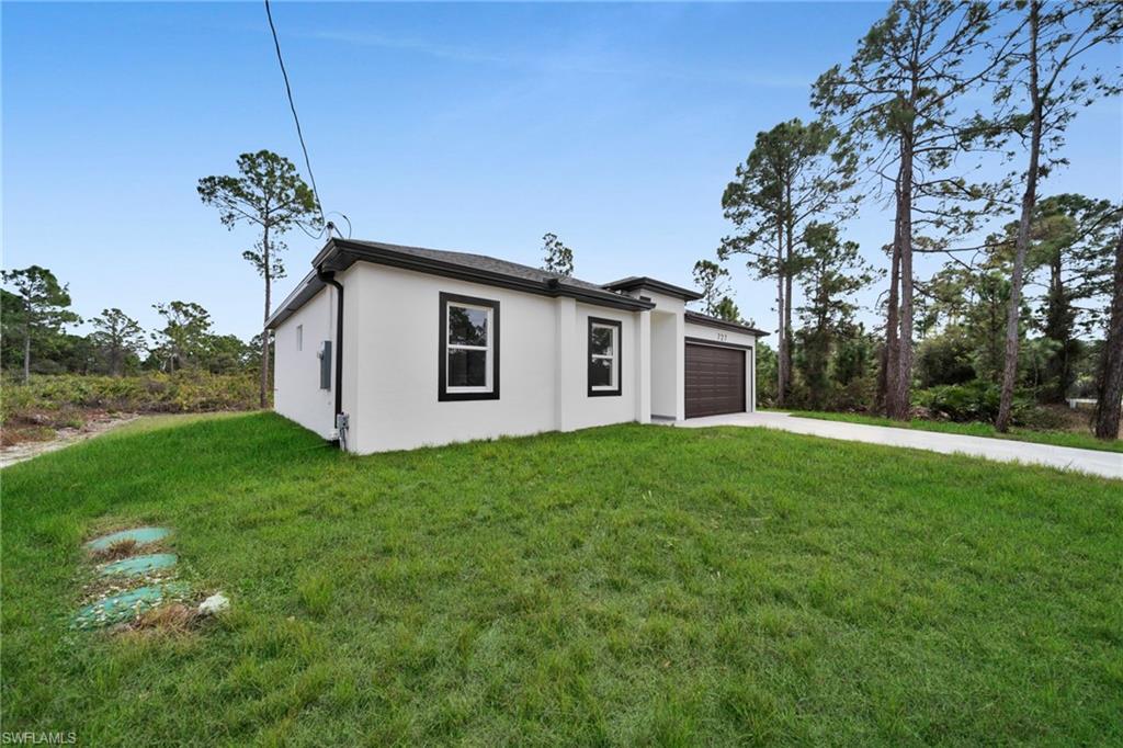 View of front of home with concrete driveway, a front lawn, stucco siding, and an attached garage