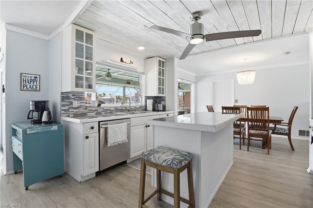Kitchen featuring white cabinetry, wood ceiling, glass insert cabinets, tasteful backsplash, and crown molding