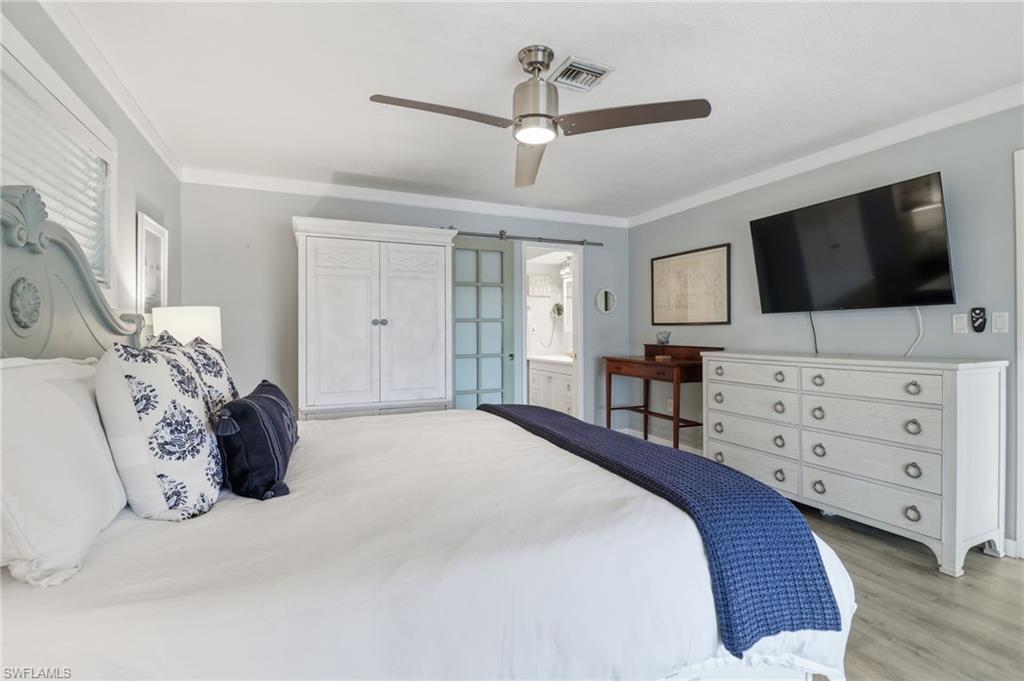Bedroom featuring crown molding, a ceiling fan, light wood-type flooring, and connected bathroom
