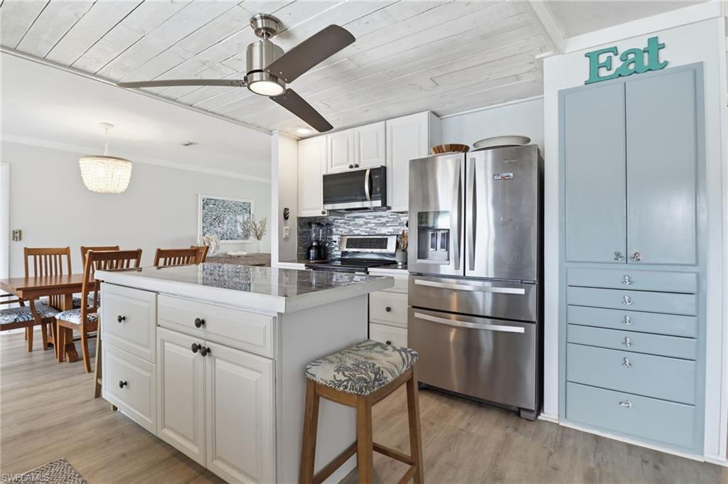 Kitchen featuring appliances with stainless steel finishes, wooden ceiling, white cabinets, backsplash, and a center island