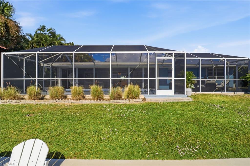 Rear view of house featuring a sunroom, glass enclosure, and a yard