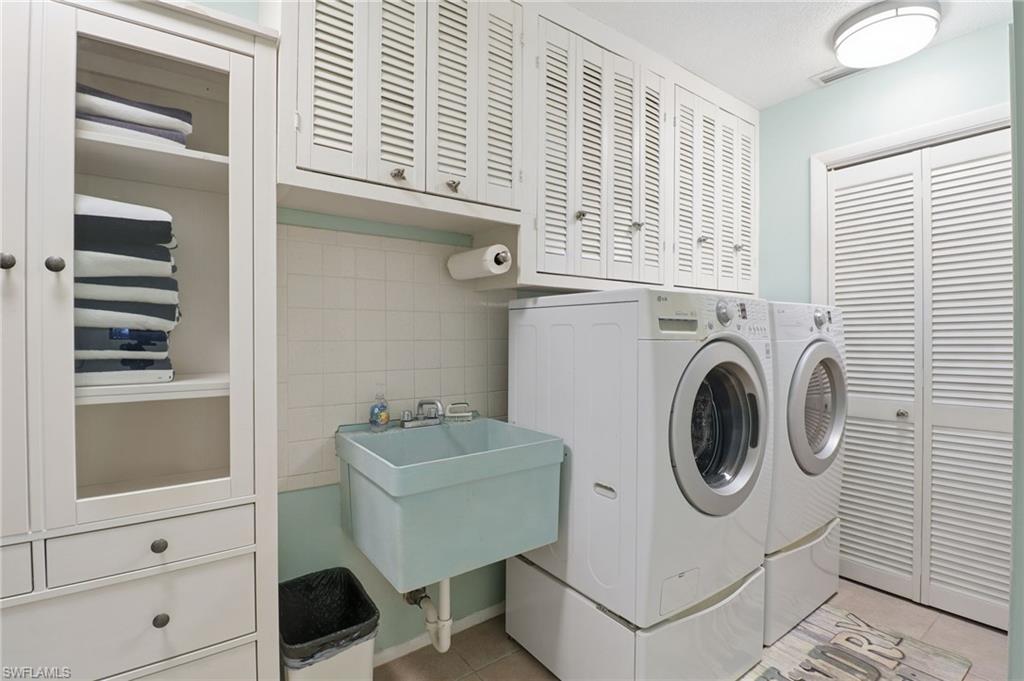 Laundry room with cabinet space, washer and dryer, light tile patterned floors, and tile walls