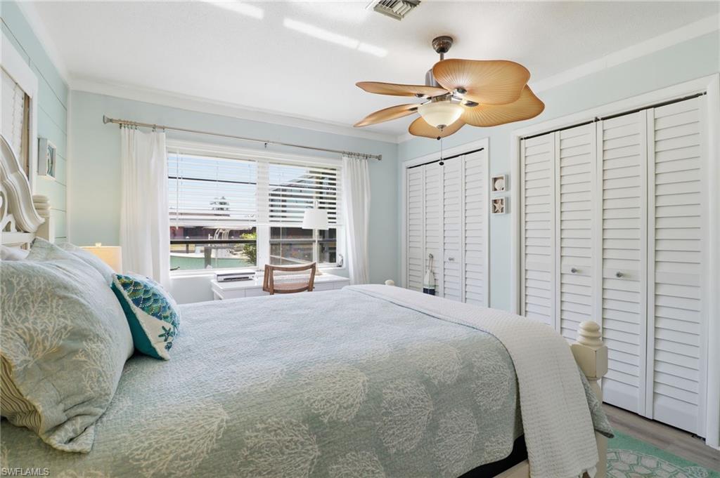 Bedroom with two closets, crown molding, ceiling fan, and wood finished floors