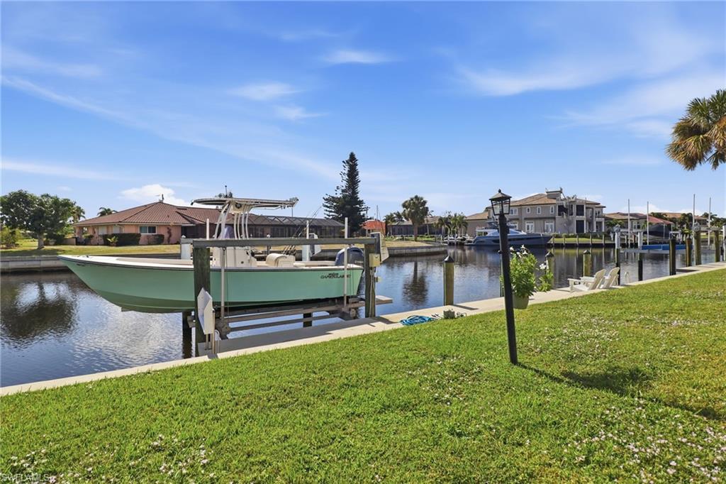 Dock with boat lift, a lawn, a water view, and a residential view