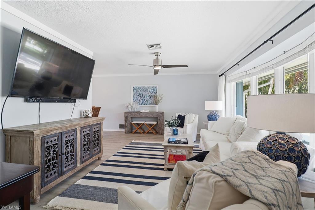 Living area with crown molding, wood finished floors, and ceiling fan