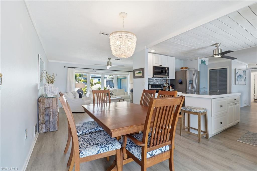 Dining area with ceiling fan, a chandelier, a fireplace, light wood-style floors, and wooden ceiling