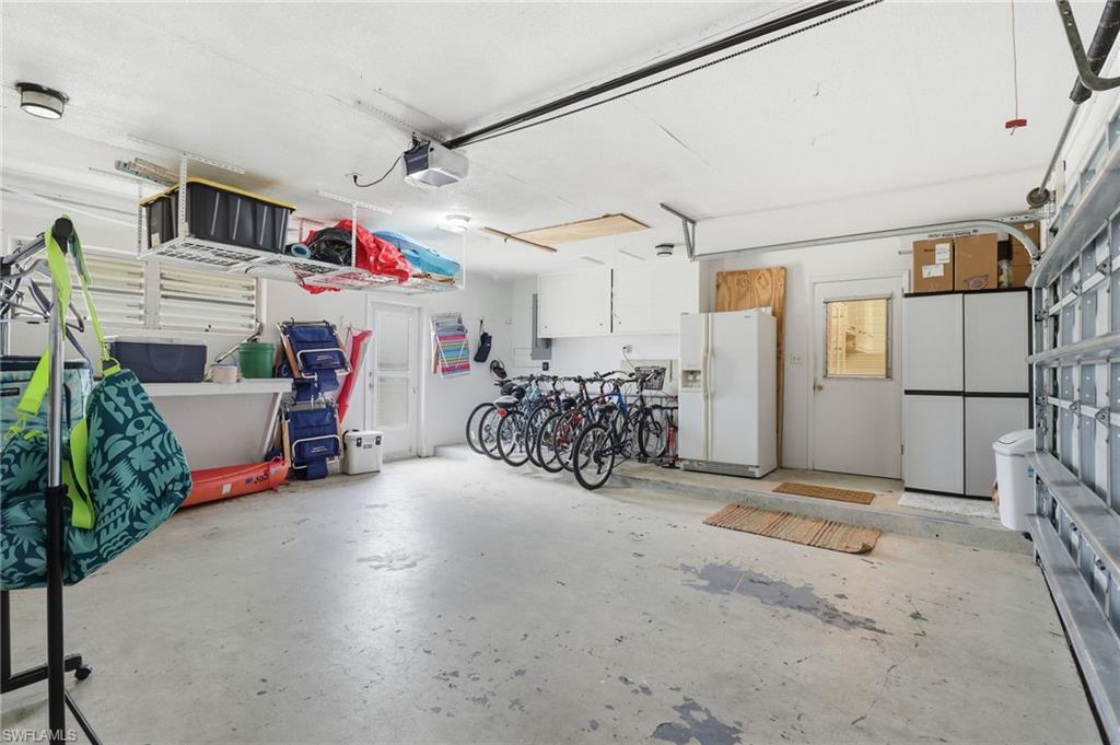 Garage with white refrigerator with ice dispenser and a garage door opener