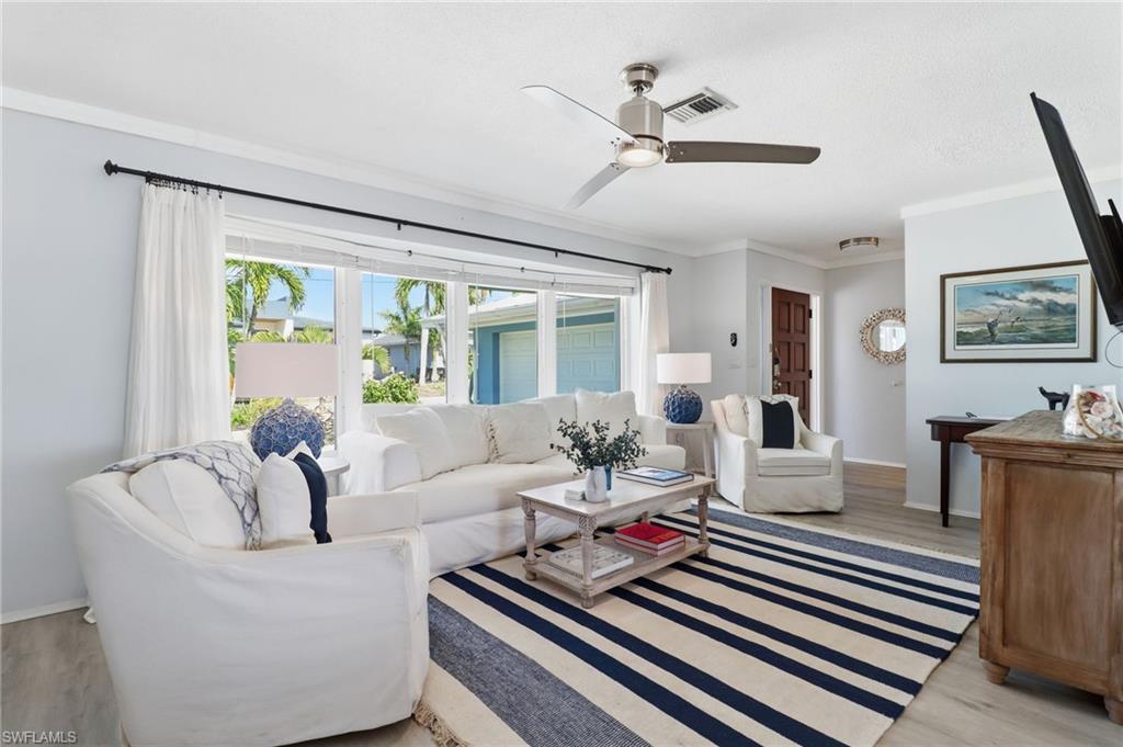 Living room featuring ornamental molding, light wood-type flooring, and ceiling fan