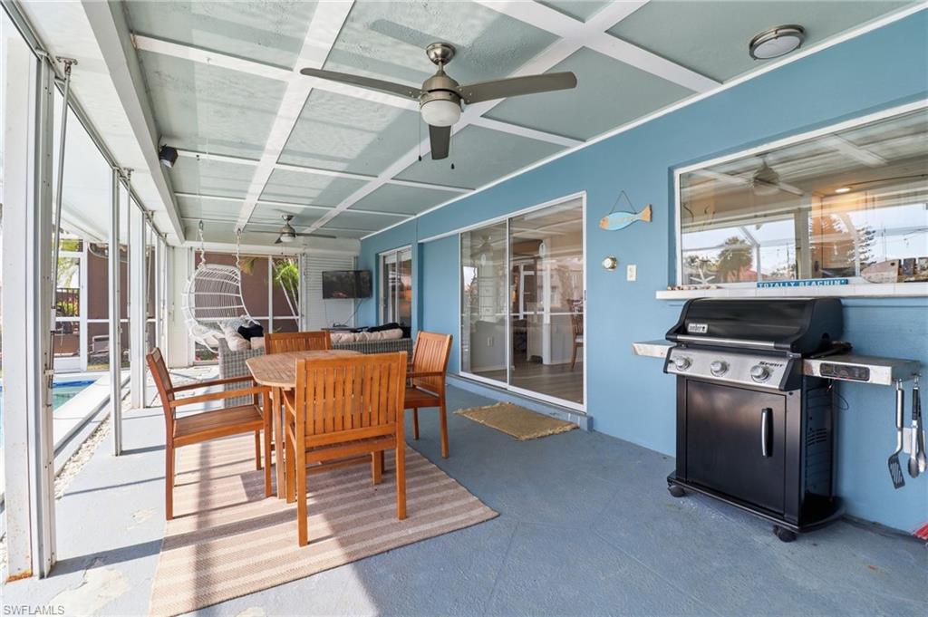 Sunroom with outdoor dining space, a patio, ceiling fan, and coffered ceiling