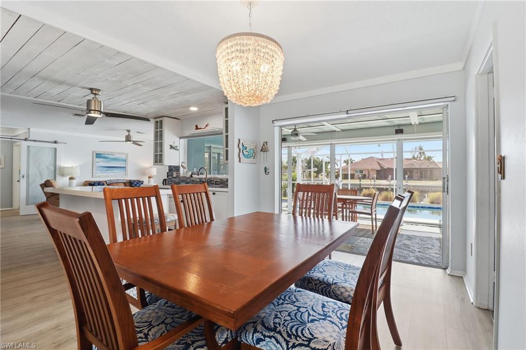 Dining room featuring a chandelier, a ceiling fan, wooden ceiling, a barn door, and a sunroom