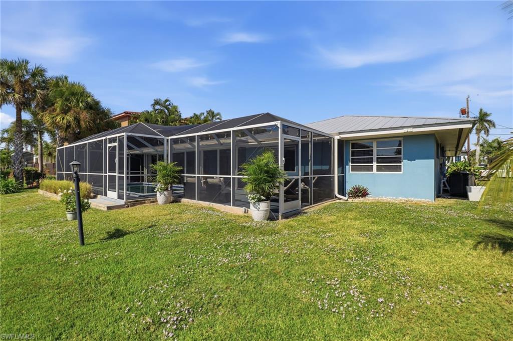 Back of property with a sunroom, a lanai, and a yard