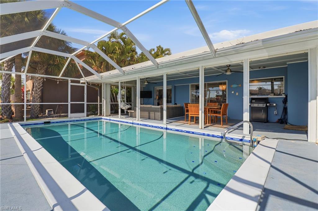 Outdoor pool featuring an outdoor living space, a sunroom, glass enclosure, and a patio area
