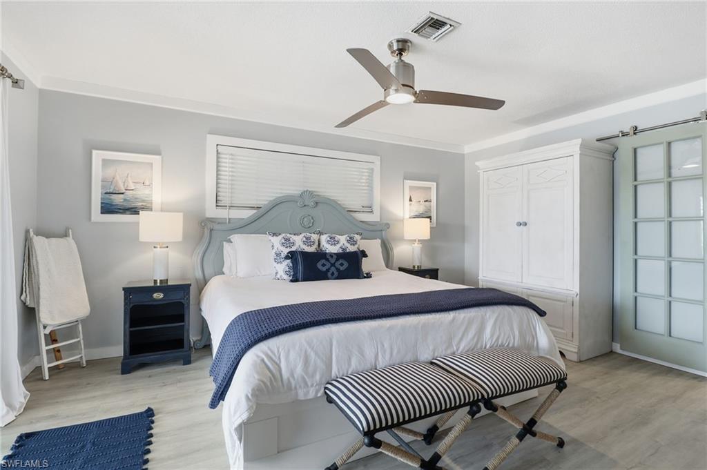 Bedroom featuring ceiling fan, a barn door, and light wood-style floors