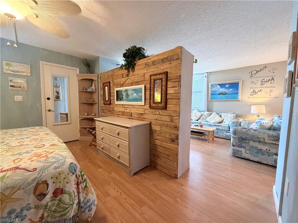 Bedroom featuring a textured ceiling, a ceiling fan, and light wood-style flooring