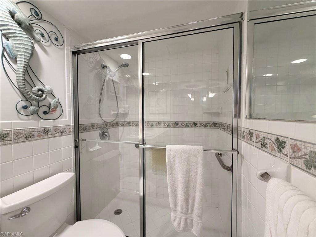 Full bath with tile walls and a shower stall