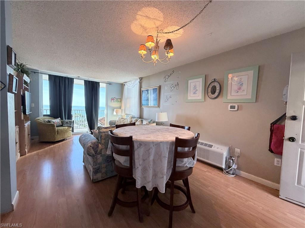 Dining room with a wall of windows, a textured ceiling, wood finished floors, and a chandelier