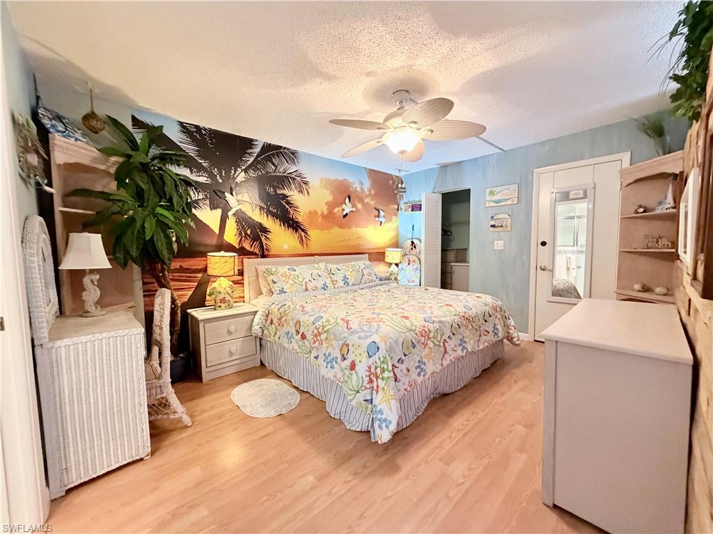 Bedroom featuring a textured ceiling, light wood finished floors, and ceiling fan