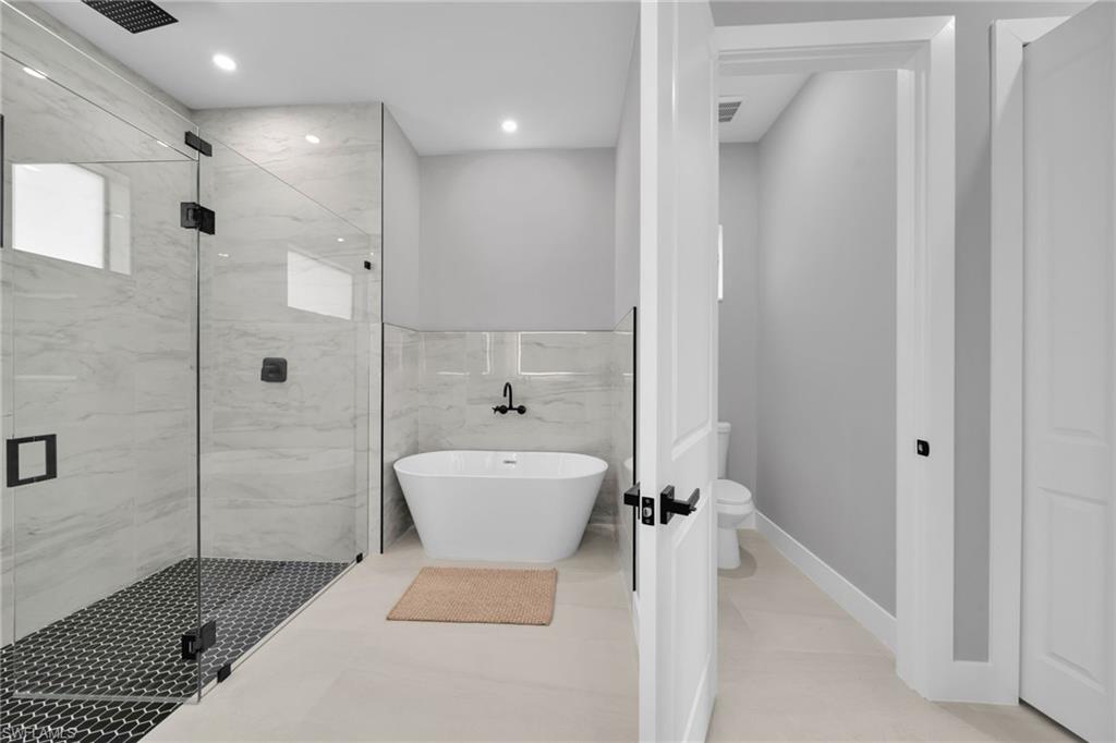 Bathroom with a freestanding tub, a marble finish shower, and recessed lighting