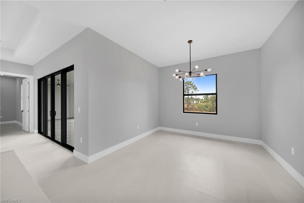Empty room featuring a chandelier and baseboards