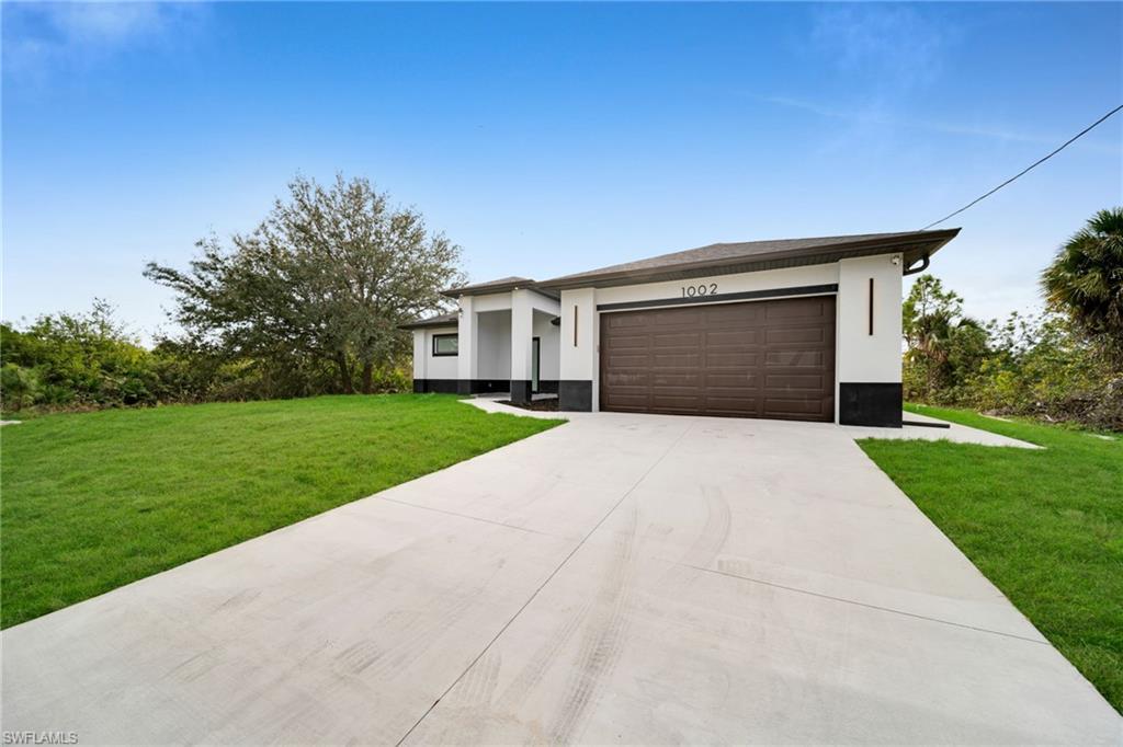 Prairie-style house with a front yard, concrete driveway, an attached garage, and stucco siding