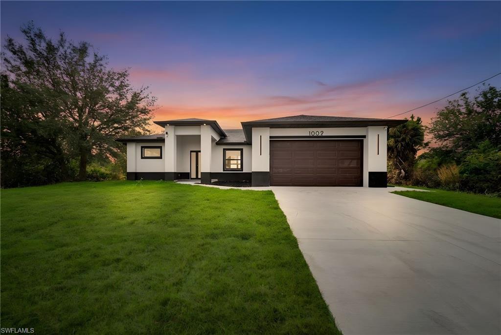 Prairie-style house featuring driveway, a garage, stucco siding, and a lawn