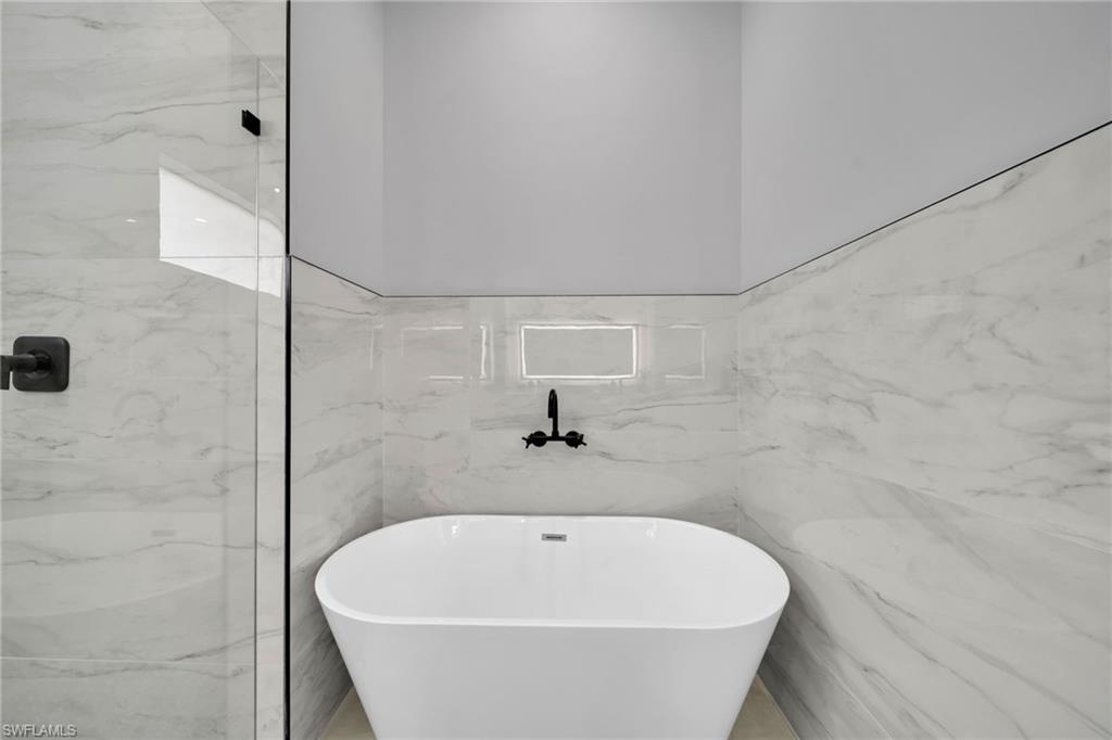 Full bath featuring a soaking tub and marble tiled floors