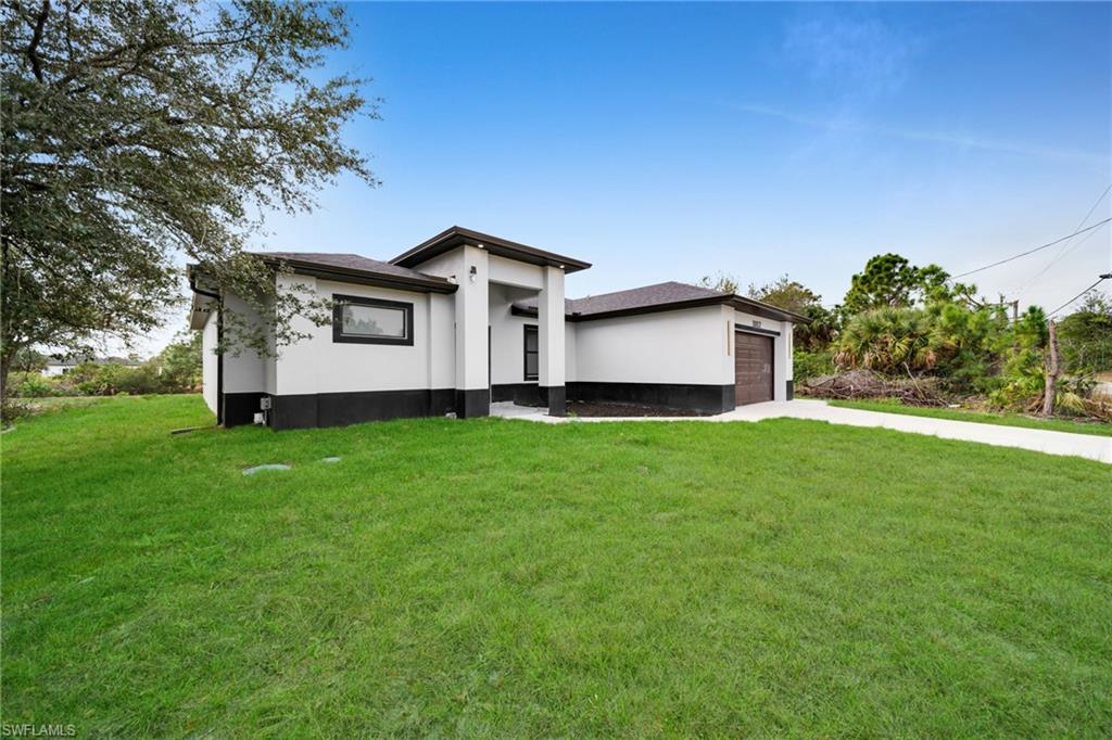Prairie-style home featuring concrete driveway, a front yard, stucco siding, and an attached garage