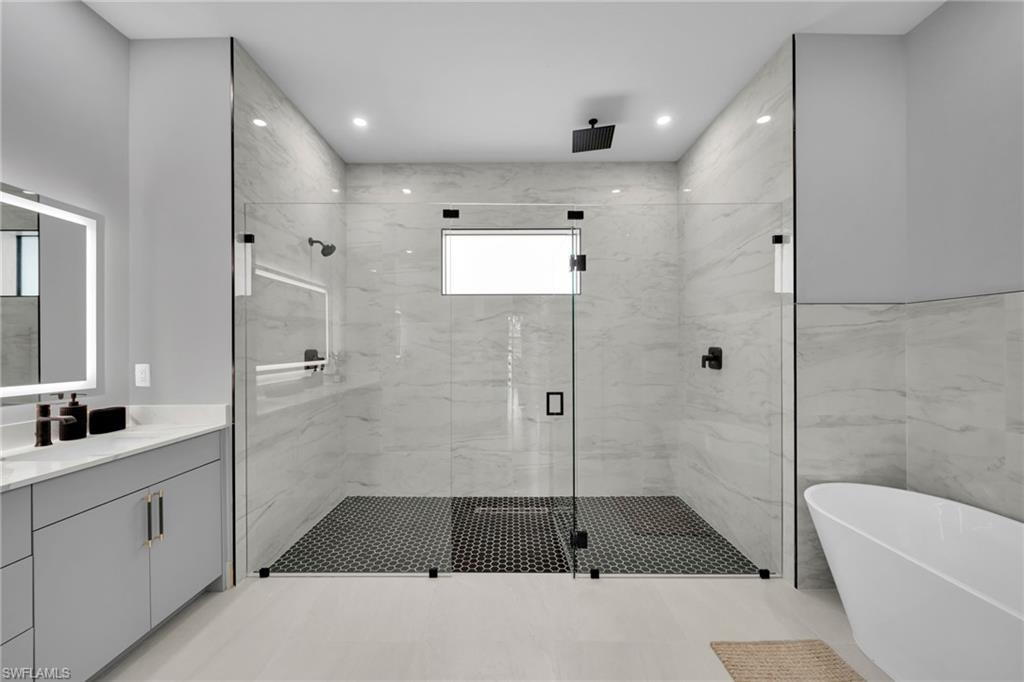 Bathroom with a freestanding tub, a marble finish shower, vanity, and recessed lighting