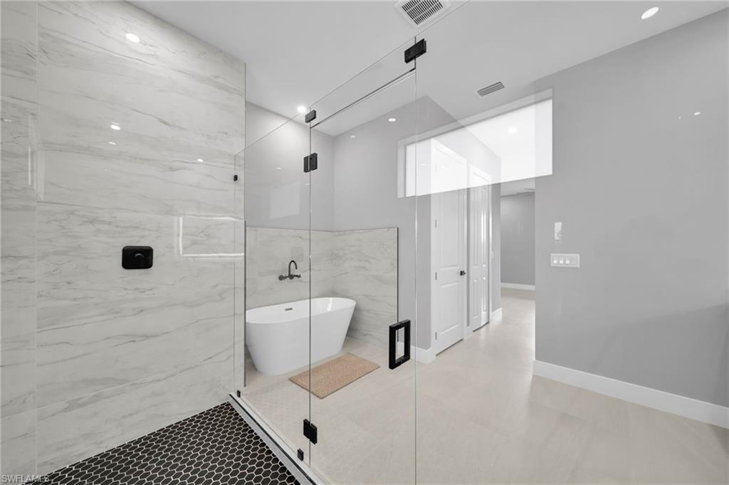 Full bathroom with a soaking tub, a marble finish shower, and a closet