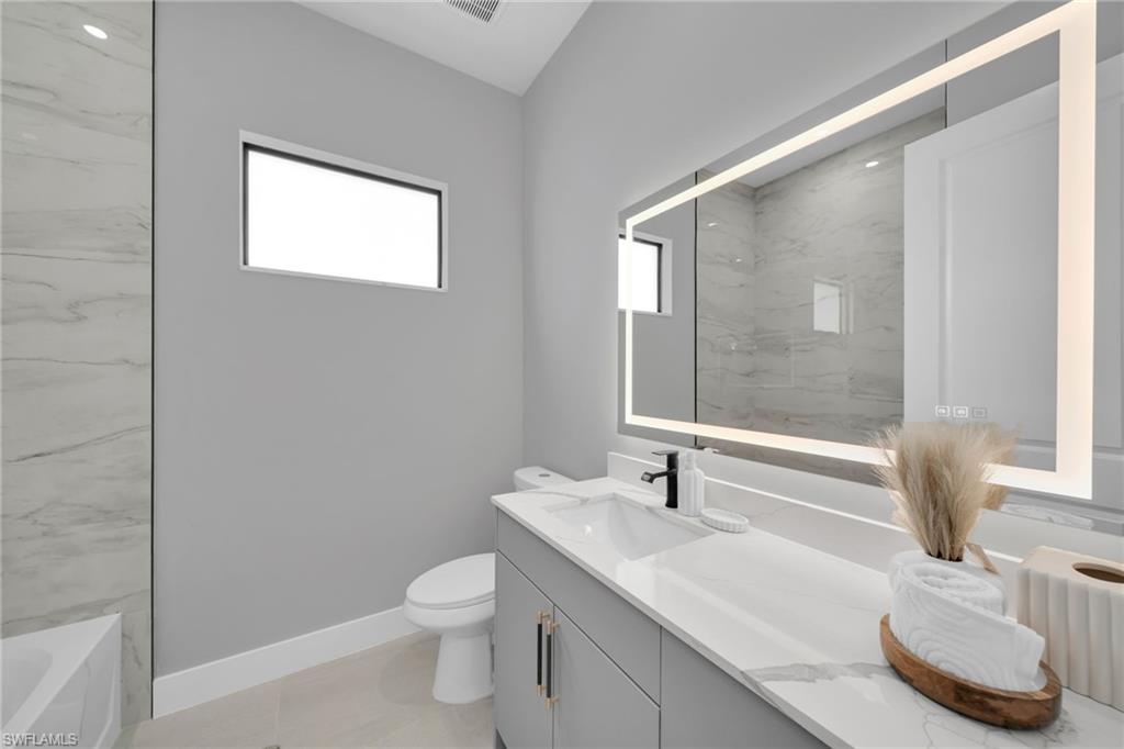 Full bathroom with vanity, plenty of natural light, a bath, and a marble finish shower