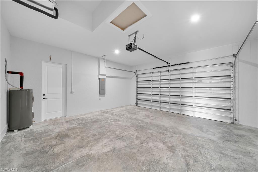Garage featuring electric panel, electric water heater, and a garage door opener