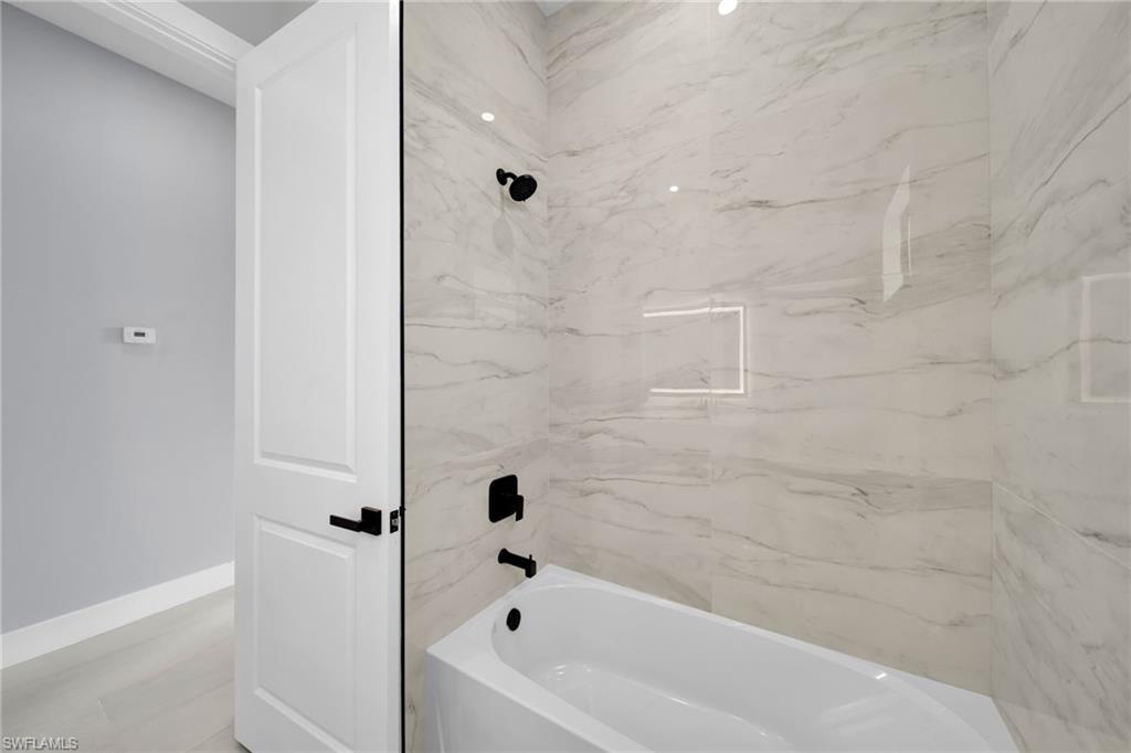 Full bath with a combined bath / shower with marble appearance and baseboards