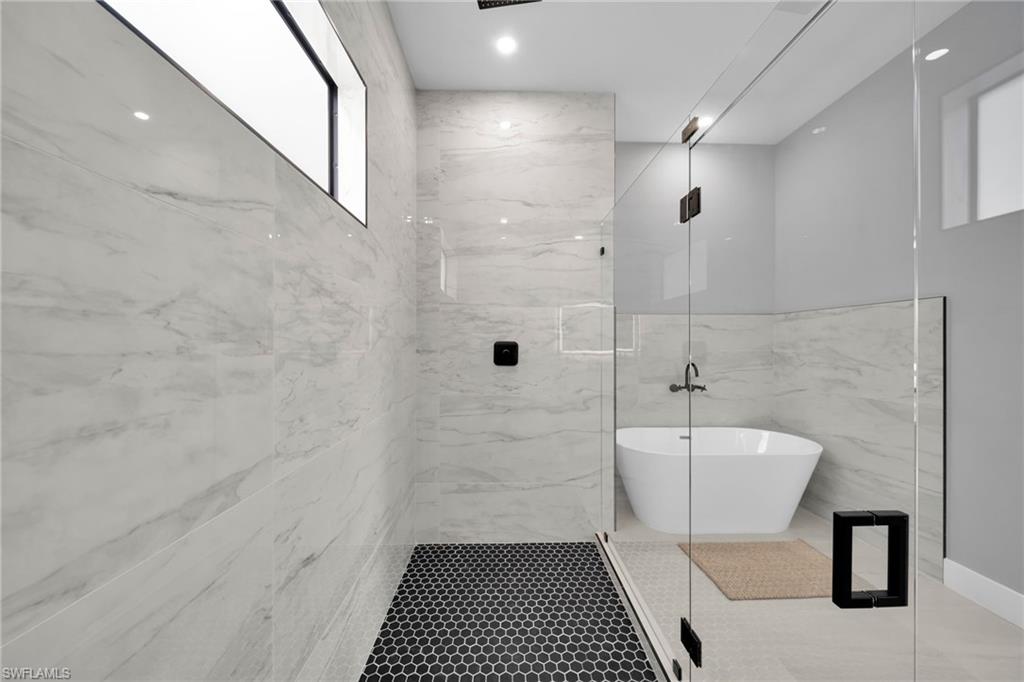 Bathroom with a marble finish shower, a freestanding tub, and tile patterned floors