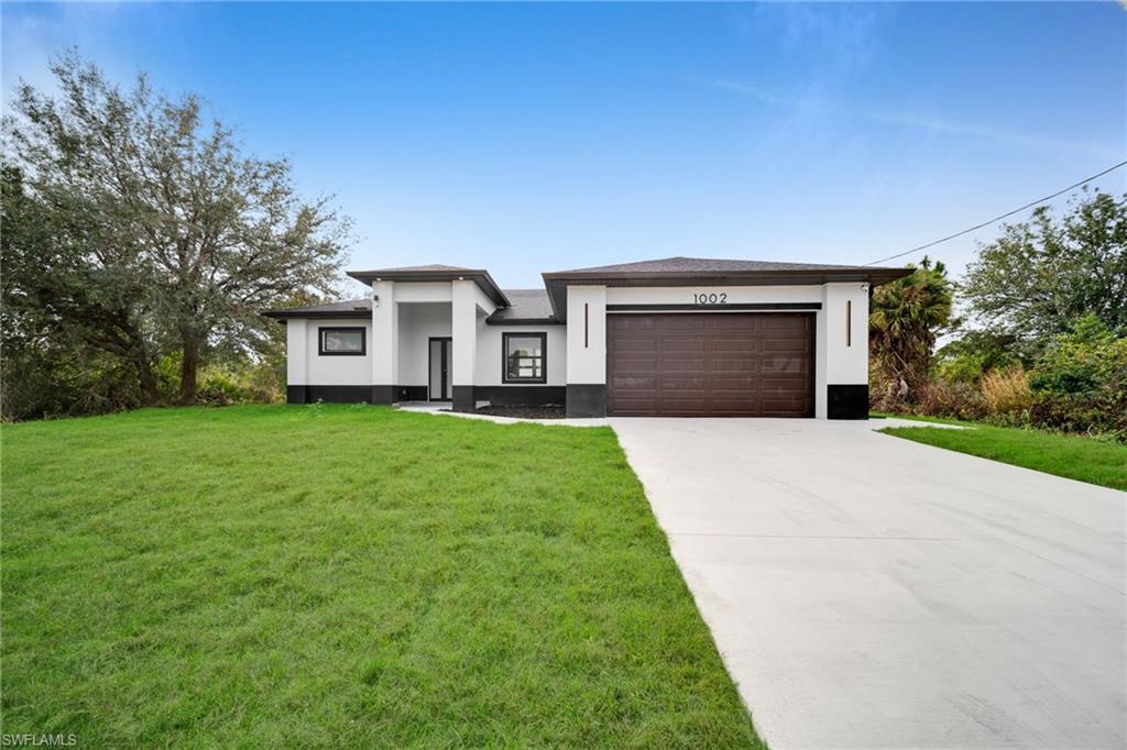 Prairie-style house with driveway, stucco siding, a front yard, and an attached garage