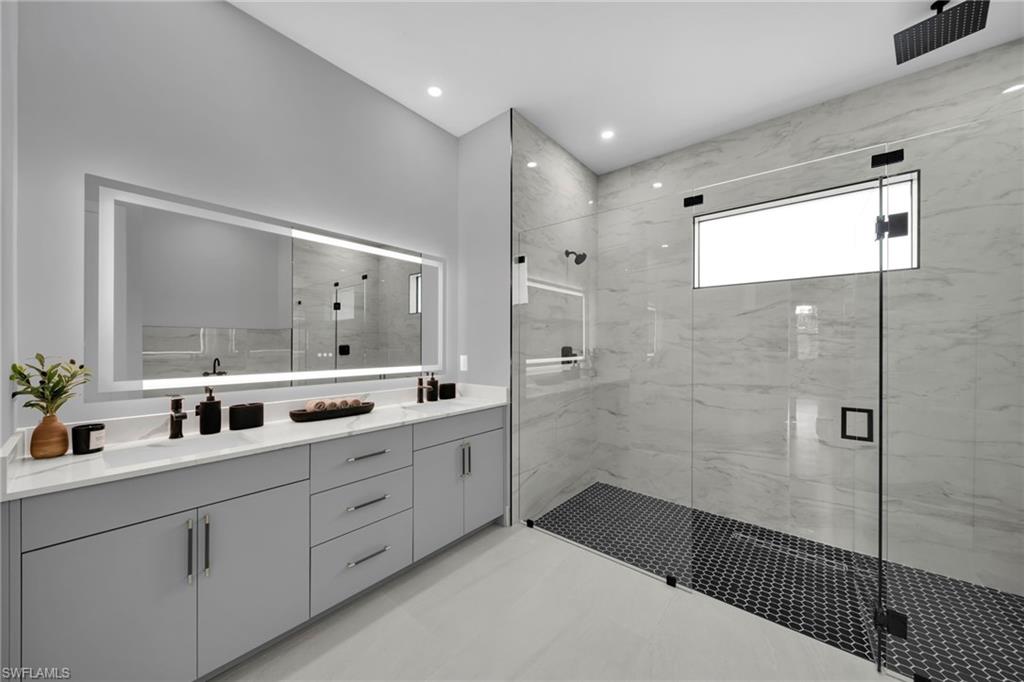 Bathroom with double vanity, a marble finish shower, and recessed lighting